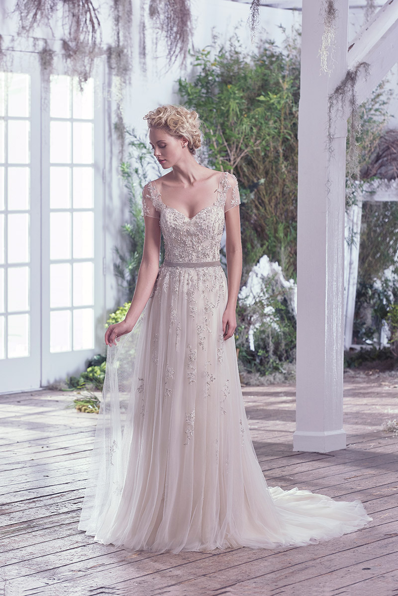 Maggie Sottero Kylie: Ethereal elegance is found in this weightless tulle and metallic embroidered lace sheath wedding dress. Swarovski crystals and beading accent the sweetheart neckline, adding whimsy and romance. Precise detailing delicately adorns illusion lace short sleeves and back. $1,699 at Brides 2 Be By Hope Mitchell.  