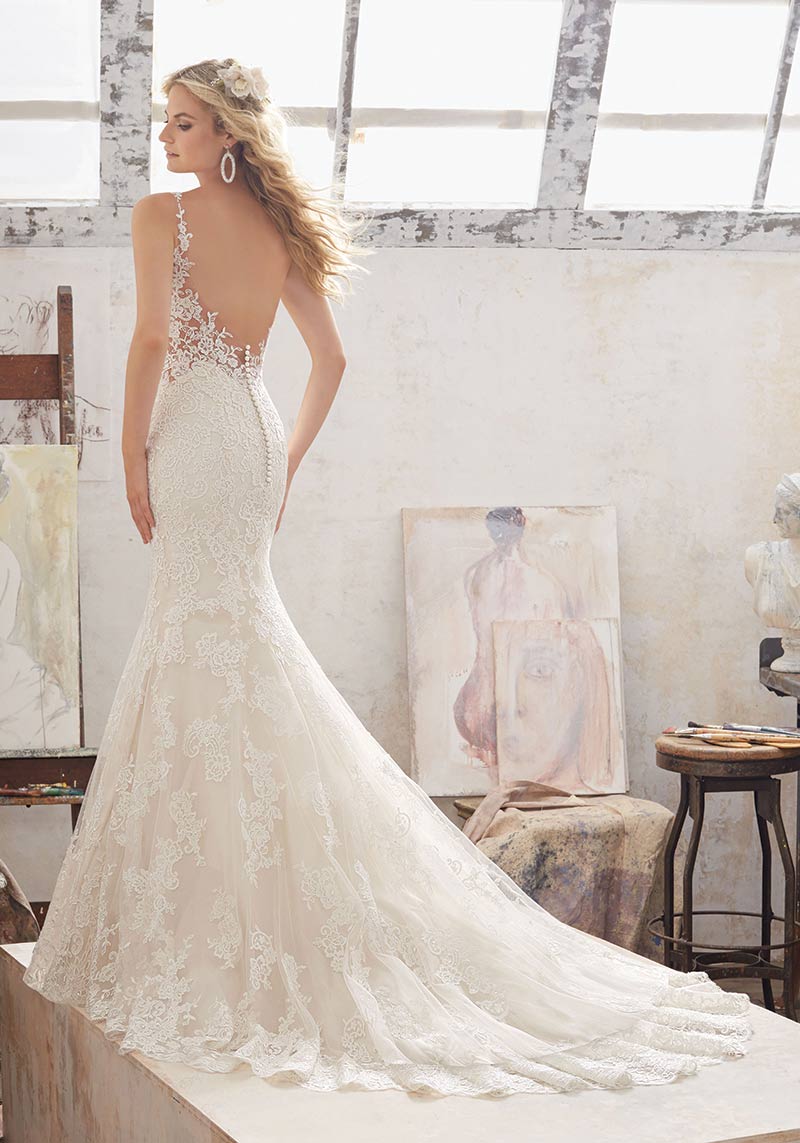 (Mori Lee Bridal Style 5462) Fit-and-flare gown features a
sleeveless silhouette with an embroidered illusion panel and a pearl and crystal beaded scoop neckline that forms two crisscrossing straps in back. Trimmed with a row of covered buttons, the back dips into a low V-shape, making the embellished back straps the focal point from the rear view. 
$975, The Dress Matters, Media, Pa., www.thedressmatters.com.